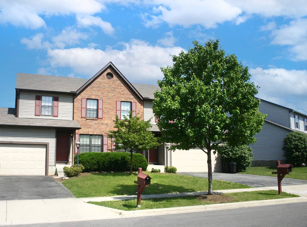 a house with a lawn and trees in front of it