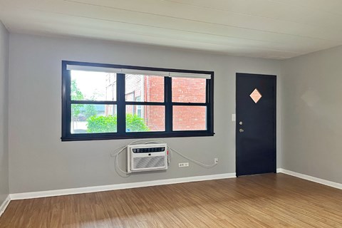 A room with a black door and a window with a view of a brick building outside.