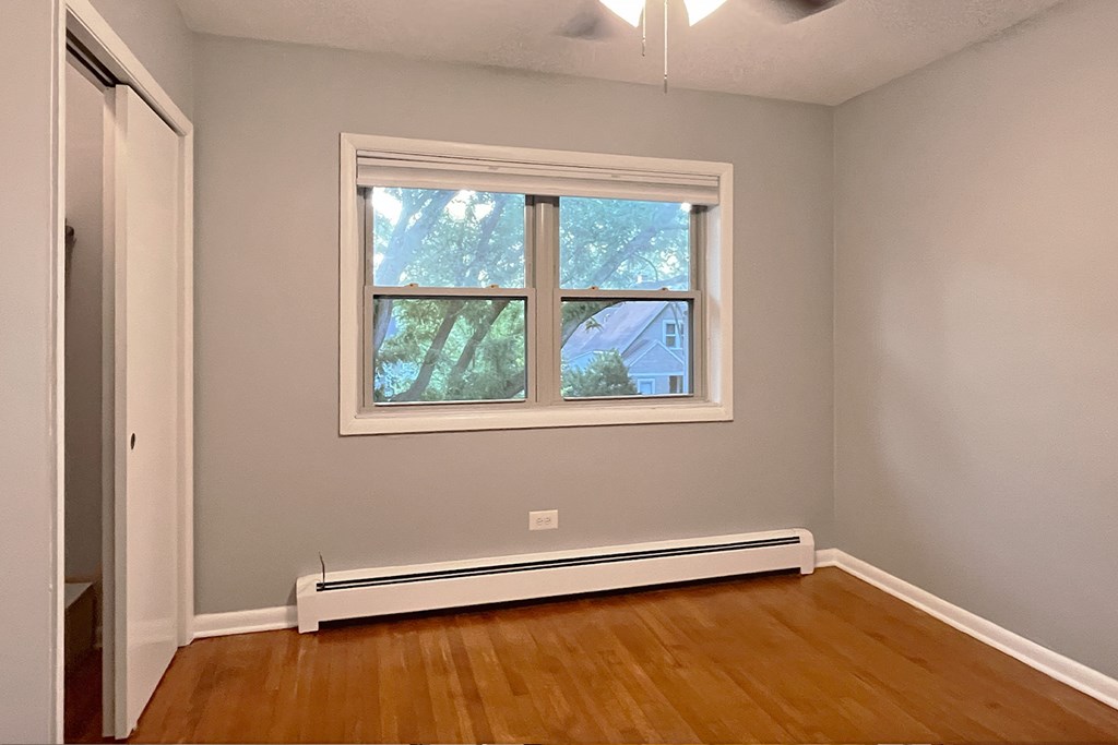 A room with a window and a white radiator on the floor.