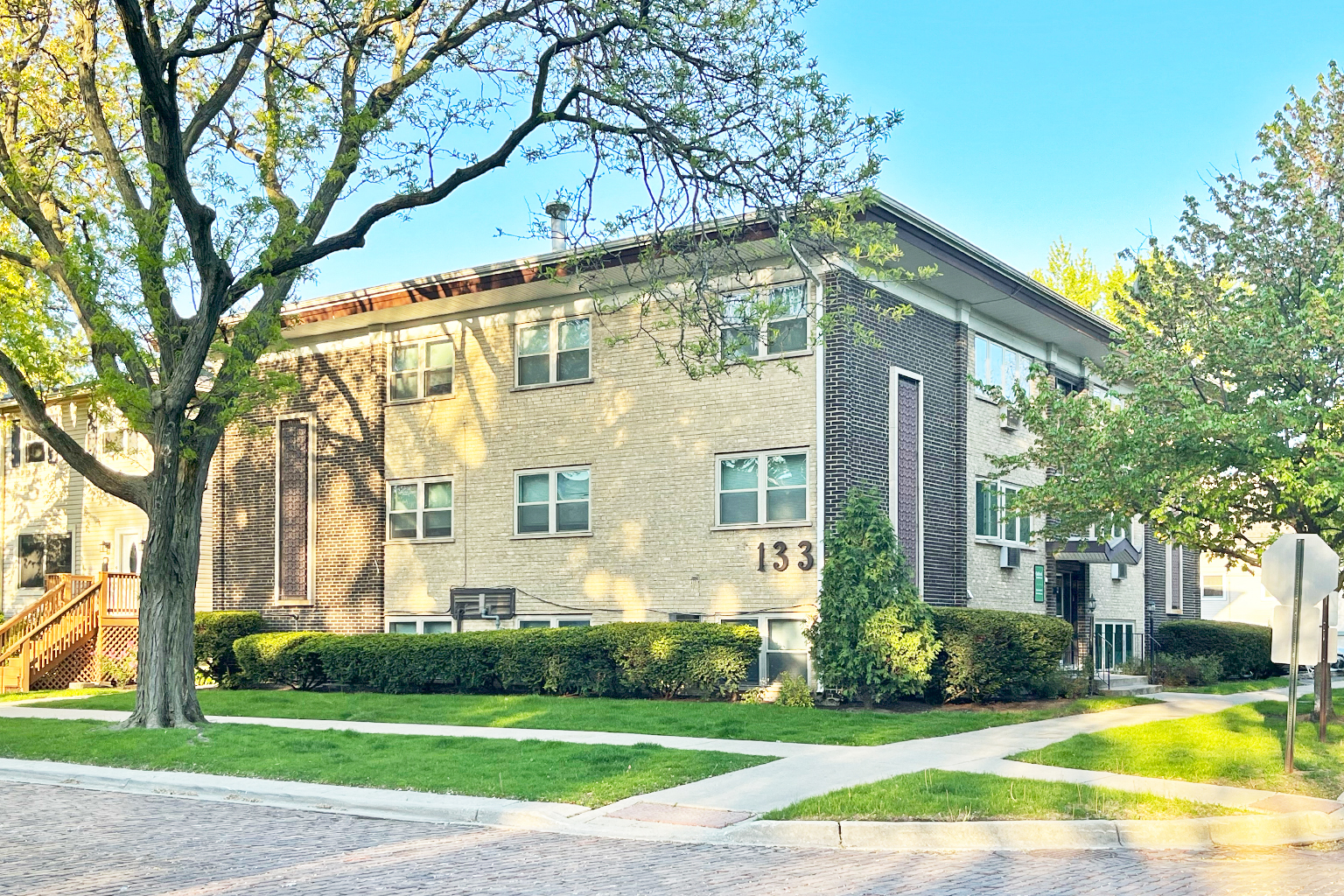 A building with the number 133 on it is surrounded by trees and bushes.