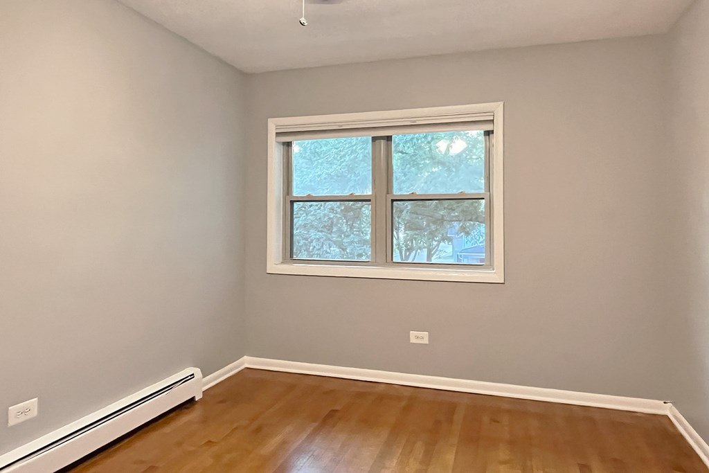 A room with a window and a radiator on the floor.