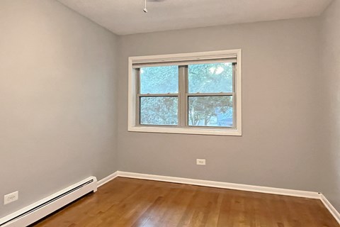 A room with a window and a radiator on the floor.