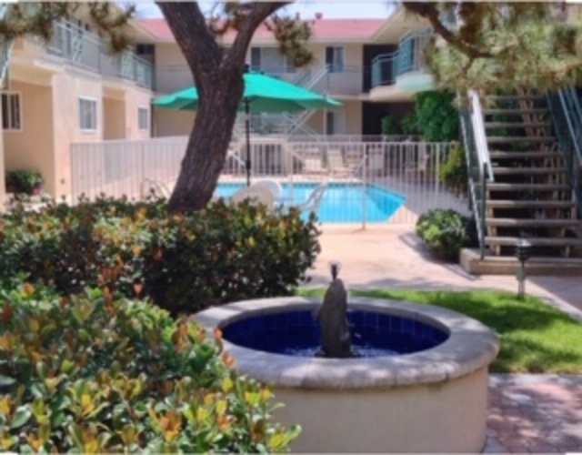 A pool with a fountain in the middle of a grassy area.