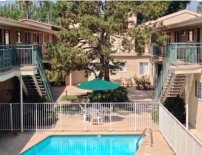 A pool with a green umbrella in the middle of a patio.
