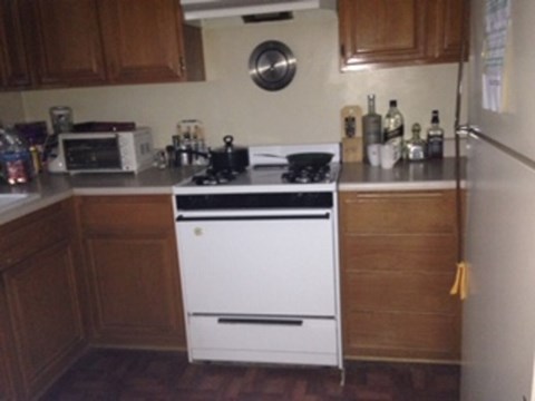 A white stove in a kitchen with wooden cabinets.