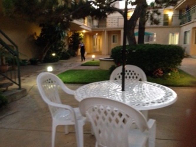 A white plastic table and chairs are set up on a patio.