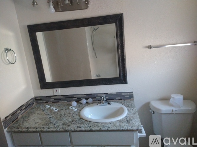 A bathroom with a granite countertop and a mirror above a sink.
