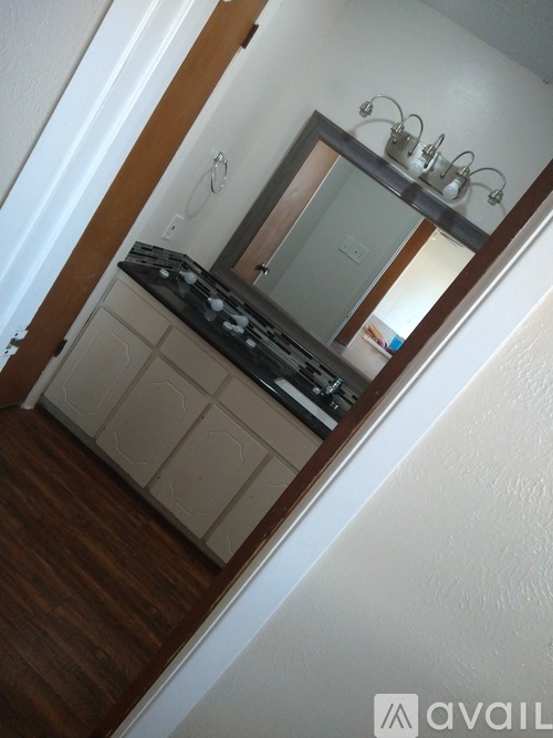 A mirror with a light above it is on a cabinet.