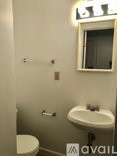 A bathroom with a toilet, sink, and mirror.