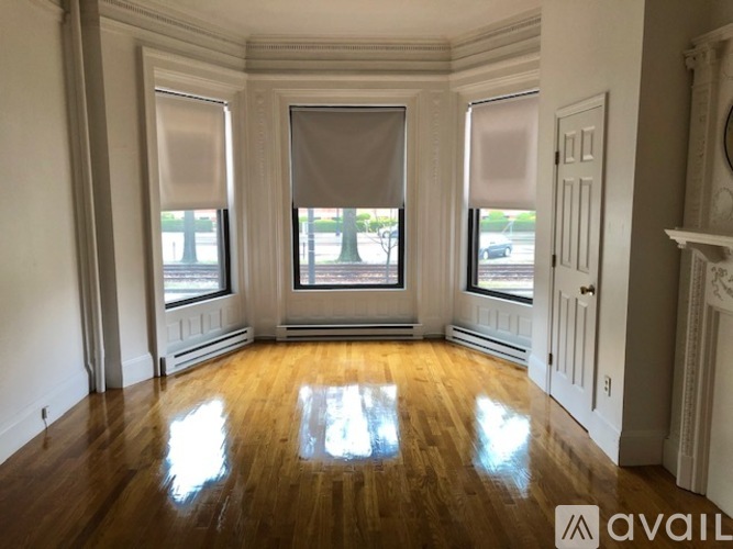 A room with wooden floors and white walls, with a large window in the middle.