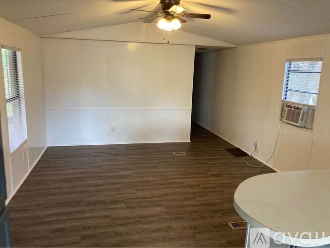 A room with a ceiling fan and wooden flooring.