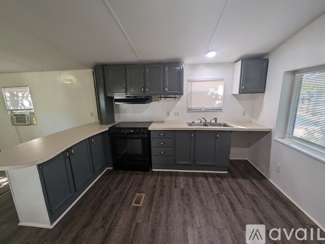 A kitchen with dark wood flooring and white walls.