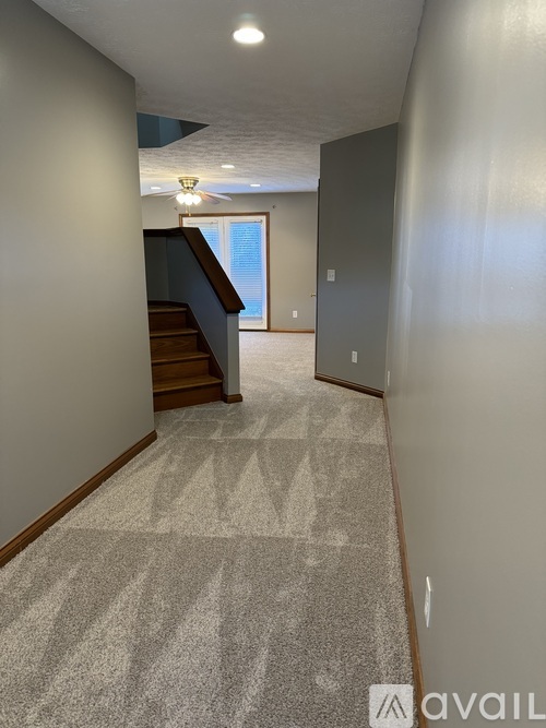 A hallway with a carpeted floor and a staircase.