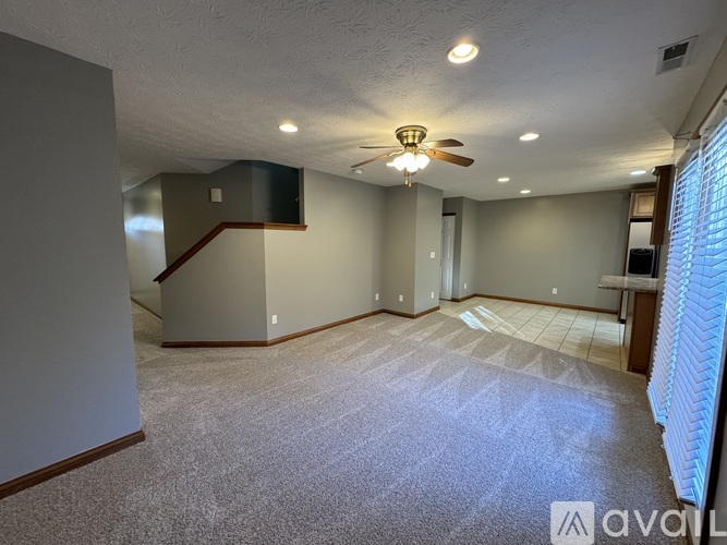 A spacious room with a ceiling fan and carpeted floor.