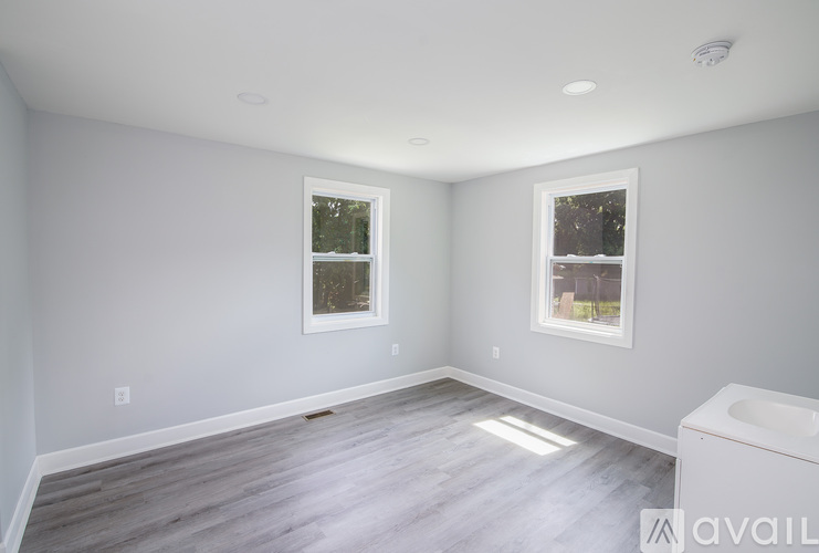 A spacious room with light grey walls and a wooden floor.
