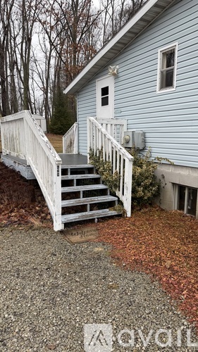 A blue house with a white railing and steps leading to the front door.