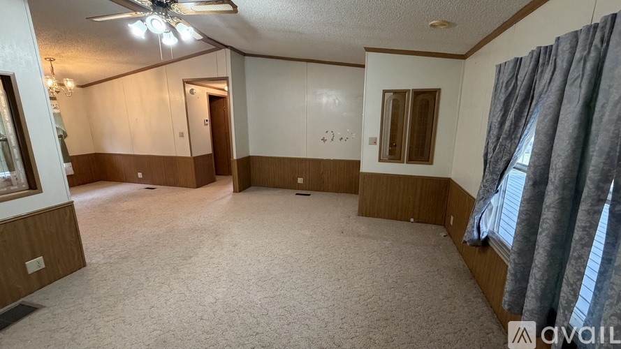 A living room with a carpeted floor and a ceiling fan.