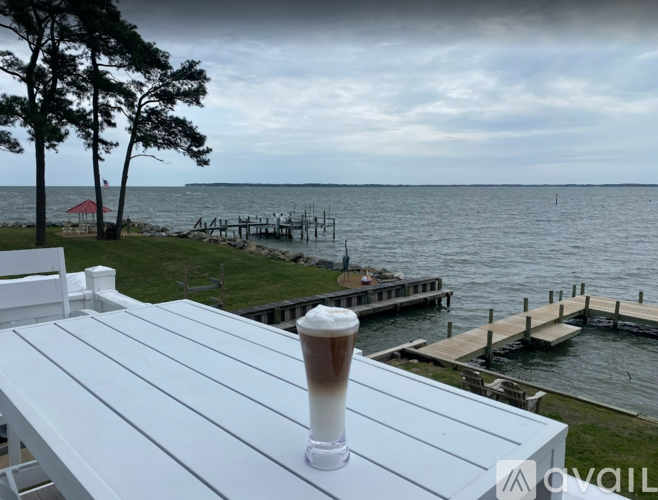 A glass of beer is on a table with a view of a dock and water.