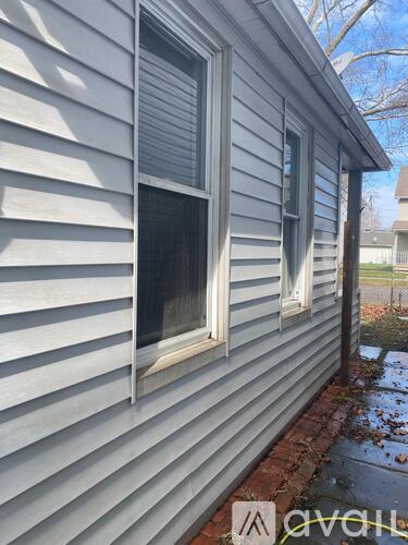 A house with a grey siding and a window with a white frame.