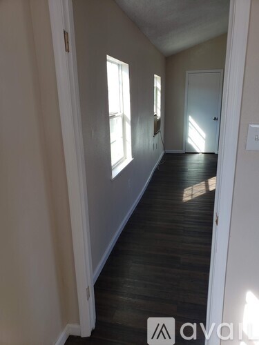 A hallway with wood floors and white walls.