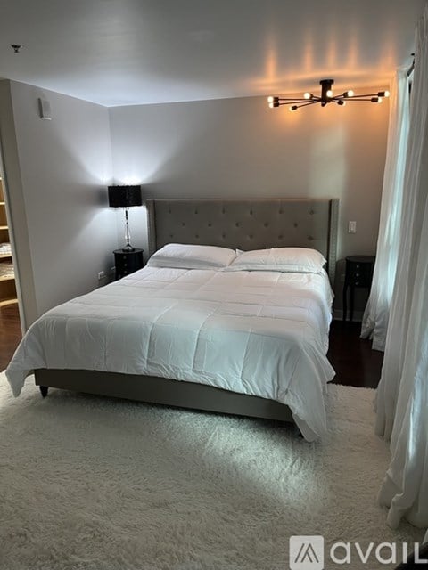 A bedroom with a white bed and a white rug.