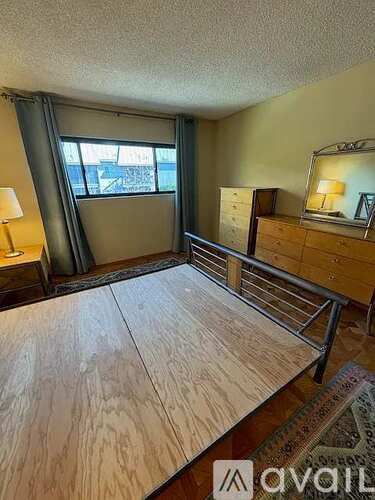 A bedroom with a large bed and a wooden dresser.