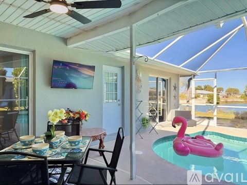 A patio with a table set for dining and a pool with a pink flamingo float.