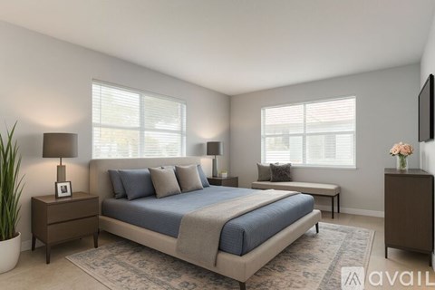 A bedroom with a bed, nightstands, and a plant.