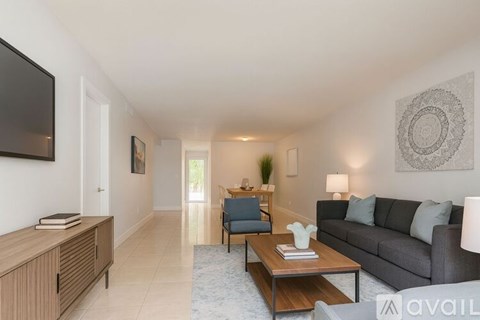 A living room with a grey couch, a wooden cabinet, a coffee table, and a television.