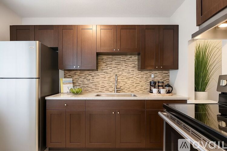A kitchen with brown cabinets and a black refrigerator.