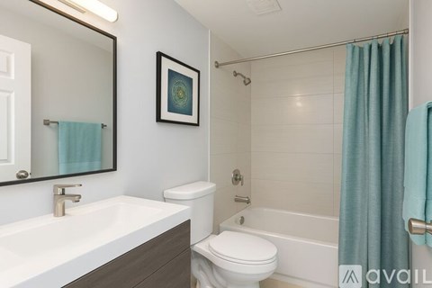 A bathroom with a white toilet, a white sink, and a blue shower curtain.
