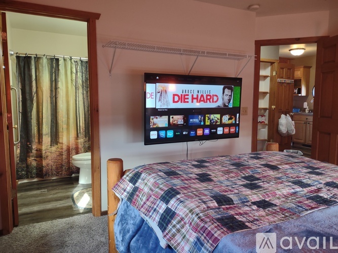 A bedroom with a bed, a television, and a window with curtains.