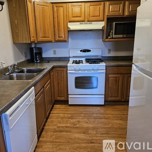 A kitchen with wooden cabinets and a white stove top oven.