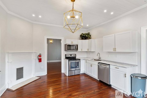 A modern kitchen with white cabinets and a wooden floor.