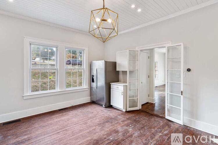 A kitchen area with a refrigerator, cabinets, and a window.