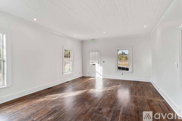 A spacious room with wooden floors and white walls.