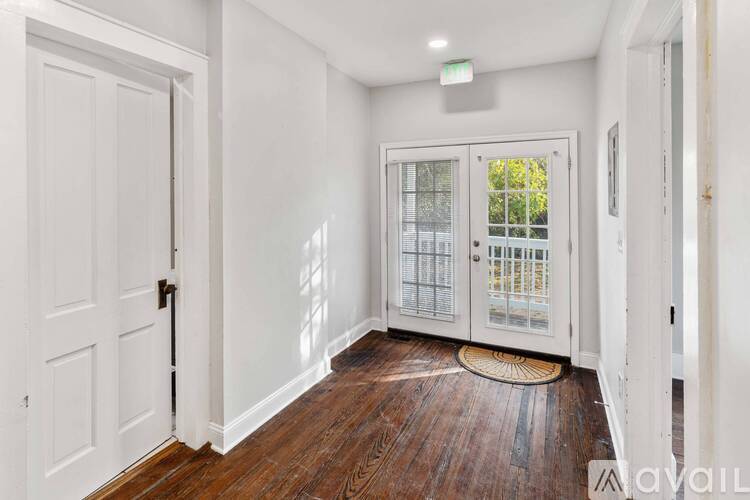 A hallway with a white door and a window with a view of trees.