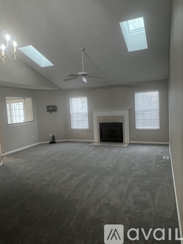 A spacious living room with a fireplace and skylights.