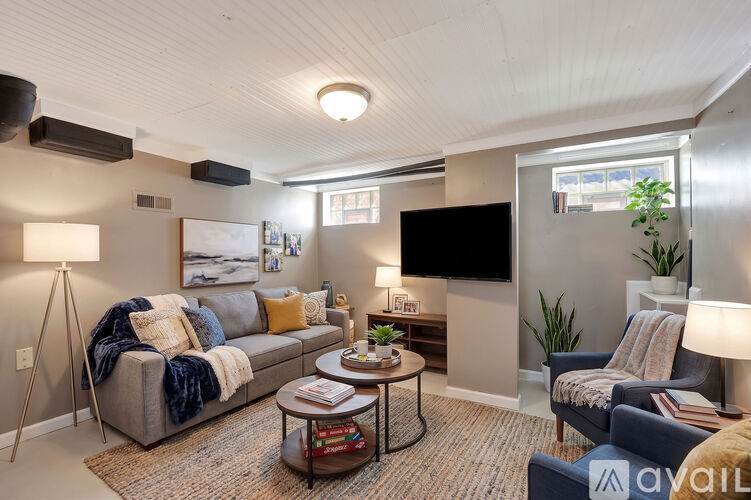 A living room with a grey couch, a black coffee table, and a flat screen TV mounted on the wall.