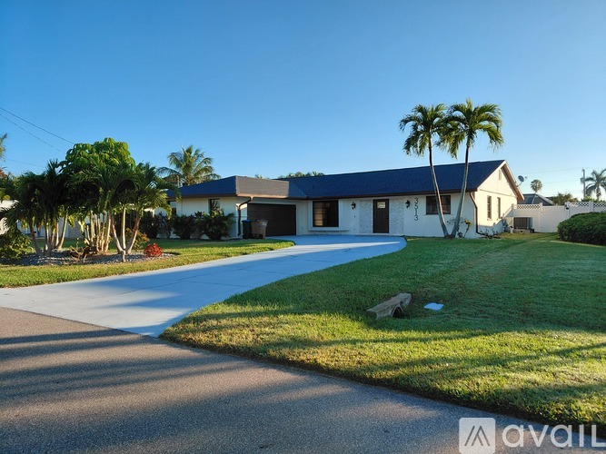 A house with a driveway and palm trees in front.