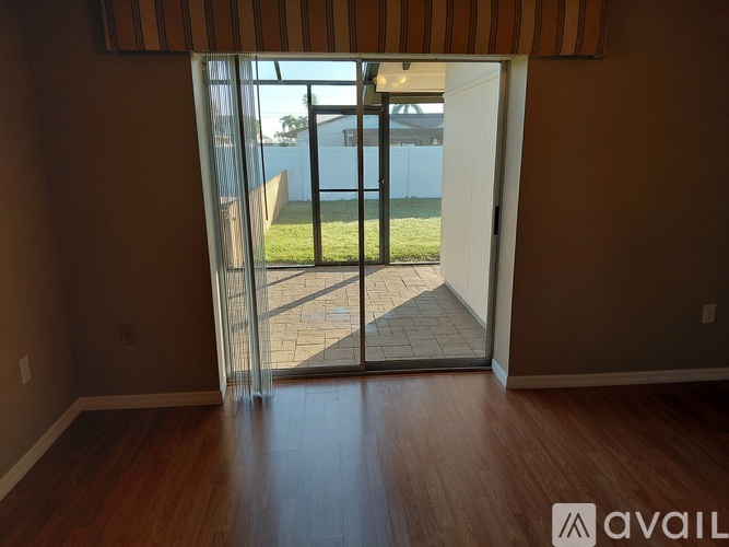 A room with a wooden floor and a sliding glass door leading to a backyard.