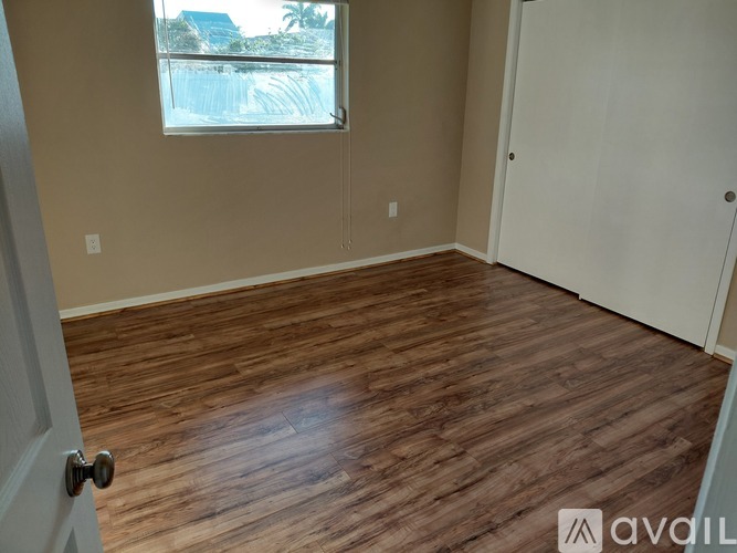 A room with wooden flooring and a window overlooking a pool.