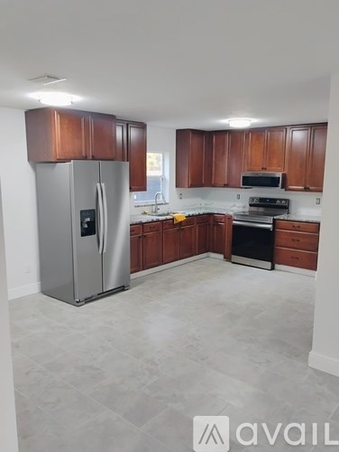 A kitchen with wooden cabinets and a stainless steel refrigerator.