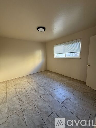 A room with a tiled floor and a window with blinds.