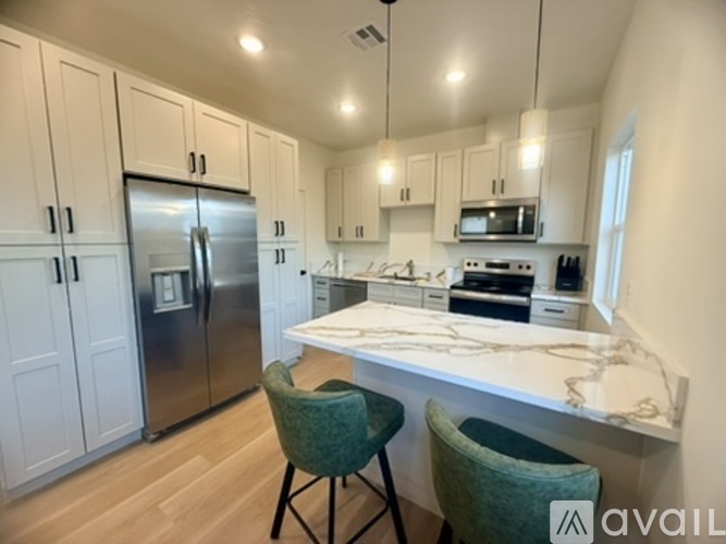 A kitchen with a refrigerator, microwave, oven, and two chairs.