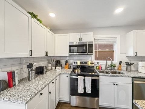 A kitchen with white cabinets and a granite countertop.