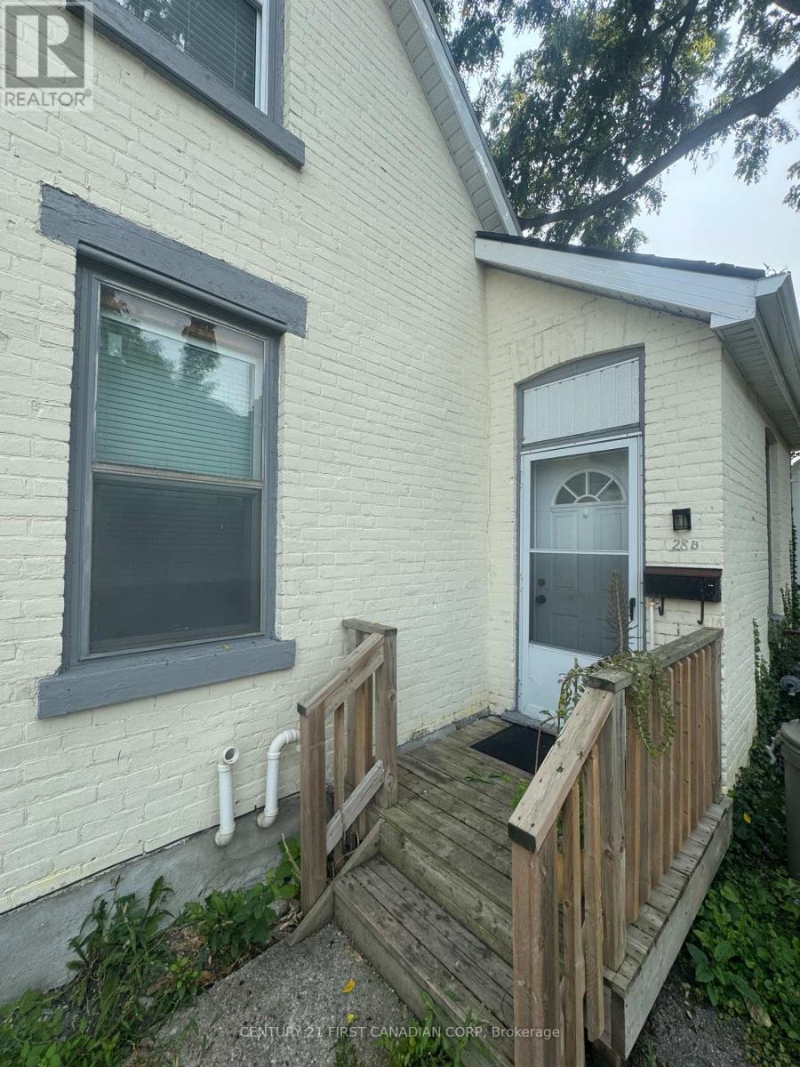 A white house with a grey window and a wooden deck.