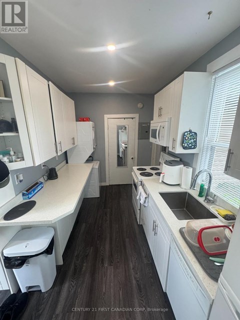 A kitchen with white cabinets and a wooden floor.