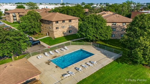 A swimming pool surrounded by lawn chairs and trees.