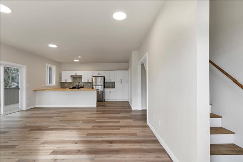 A kitchen with white cabinets and a wooden floor.